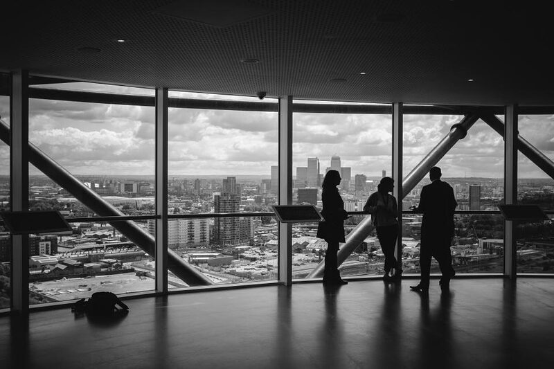 Figures silhouetted against an office window overlooking a city skyline