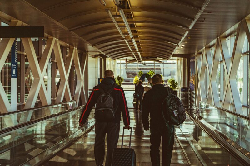 Travellers walking through an airport terminal walkway toward their gate